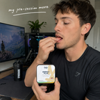 Man in a gaming setup holding a container of 'Energy Plus' supplement.